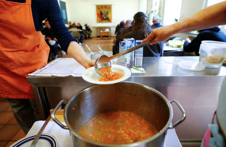 Volunteers dish out vegetable soup for people in need at the soup kitchen "Kana" in a poor district of the city of Dortmund, western Germany, April 7, 2017. REUTERS/Wolfgang Rattay