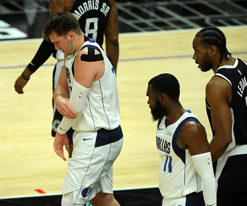 Luka Doncic winces after falling on his left arm during the first half.
