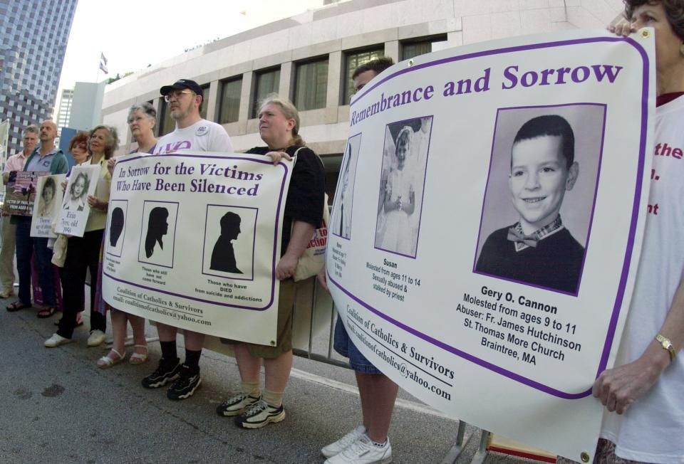 FILE - Demonstrators with the Coalition of Catholics and Survivors hold posters of children who have allegedly been sexually abused by Catholic priest, across the street from where the U.S. Conference of Catholic Bishops are meeting in Dallas, Friday, June 14. 2002. The nation's Catholic bishops begin their fall annual meeting Monday, Nov. 14, 2022, on the 20th anniversary of their adoption of policies designed to root out sexual abuse and abusers in the priesthood — policies adopted amid the scandals of 2002 when the Boston Globe's Spotlight investigative team exposed widespread patterns of abuse and coverup. (AP Photo/Charlie Riedel, File)