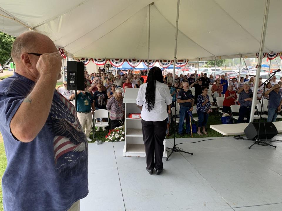 Emcee Wayne Blank Sr. salutes during the singing of the national anthem by Rosalind Gaston, a member of the auxiliary to Monroe Post 1138, VFW, during the annual Veterans Day program at the Monroe County Fair Monday.