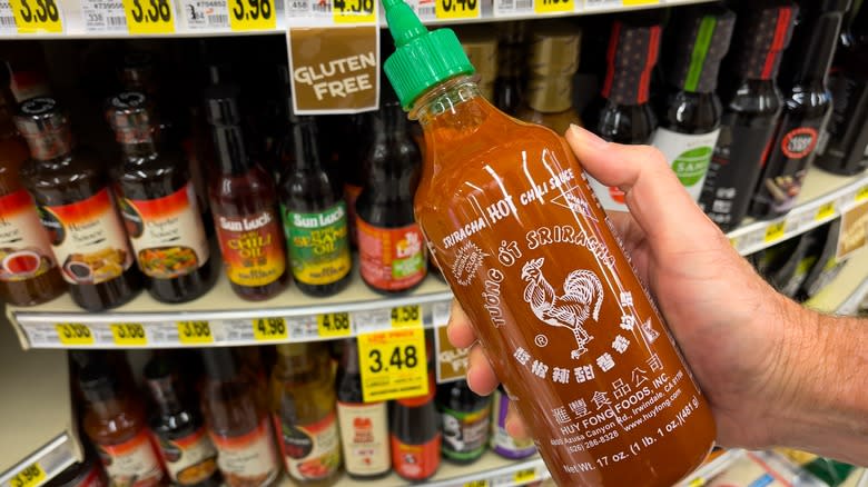 person holding bottle of sriracha 