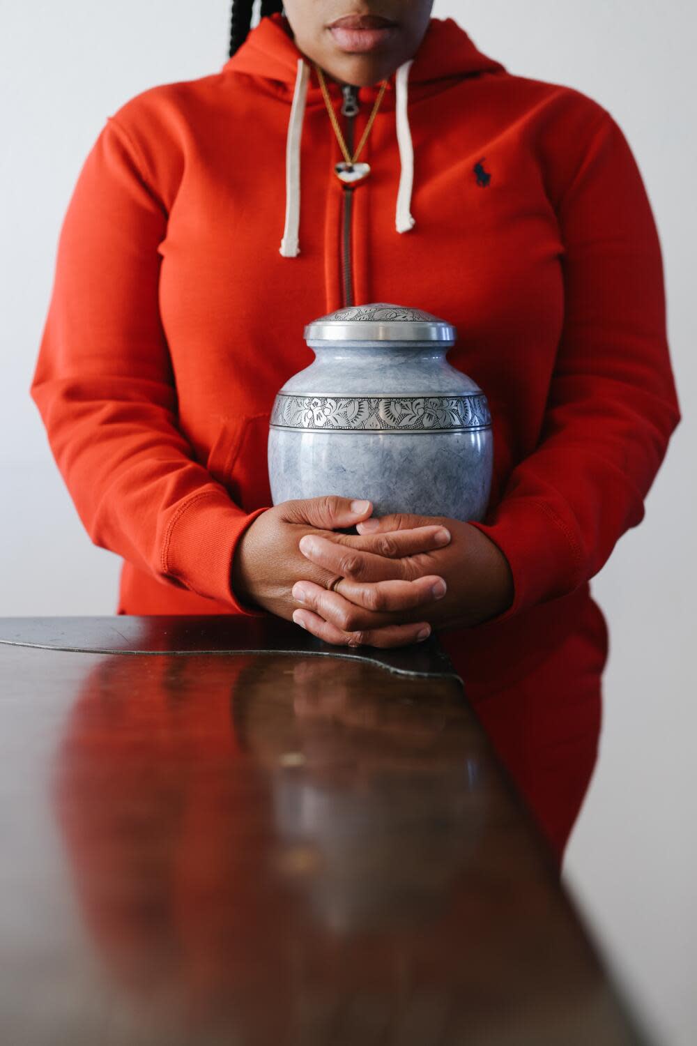 Tawana Hunter holds her father's urn at home in Lancaster. Her father, Jubal Hunter, died in custody