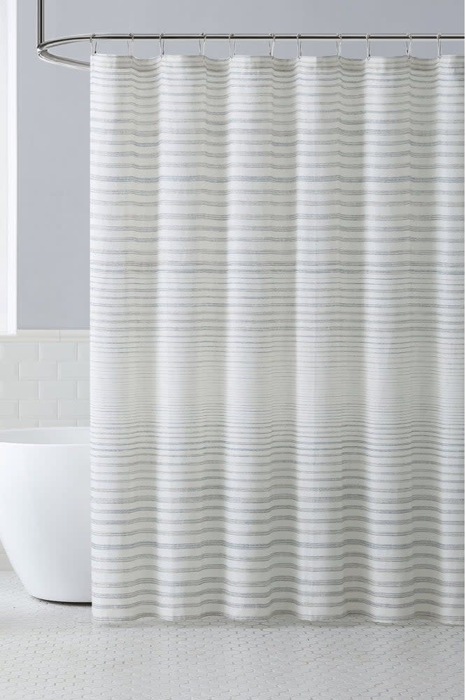 Striped shower curtain in a modern bathroom with freestanding tub and side table