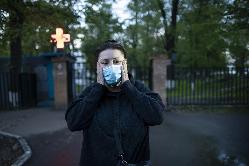 In this photo taken on Monday, May 18, 2020, Dr. Irina Vaskyanina adjusts a face mask to protect against coronavirus during her interview with the Associated Press in front of a hospital in Reutov, just outside Moscow, Russia. Vaskyanina headed a department handling blood transfusions at a hospital in Reutov, outside Moscow, and spent weeks fighting for better working conditions after 40 of her colleagues got infected with the virus and dozens quit. (AP Photo/Alexander Zemlianichenko)