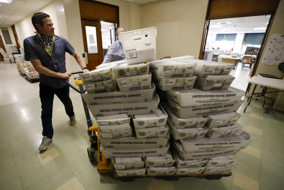 FILE - Chet Harhut, deputy manager, of the Allegheny County Division of Elections, wheels a dolly loaded with mail-in ballots, at the division of elections offices in downtown Pittsburgh, May 27, 2020. State laws in the crucial battleground states of Pennsylvania, Michigan and Wisconsin force most mail-in ballots to be processed and counted after Election Day, sometimes stretching the process by a week or more. That lag time in getting results opens the door to lies and misinformation that can sow distrust about the eventual outcome in close races. (AP Photo/Gene J. Puskar, File)
