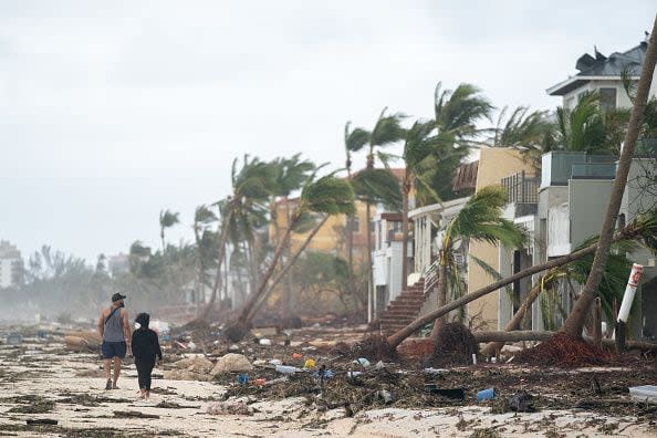People walk along the beach looking at property damaged by Hurricane Ian on Sept. 29, 2022, in Bonita Springs, Florida. The storm made a U.S. landfall on Cayo Costa, Florida, and brought high winds, storm surges, and rain to the area causing severe damage. (Photo by Sean Rayford/Getty Images)