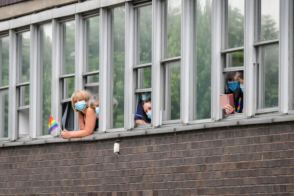 People wear masks as they watch the Prince of Wales and the Duchess of Cornwall meet other front line key workers who who have responded to the COVID-19 pandemic during a visit to Gloucestershire Royal Hospital.