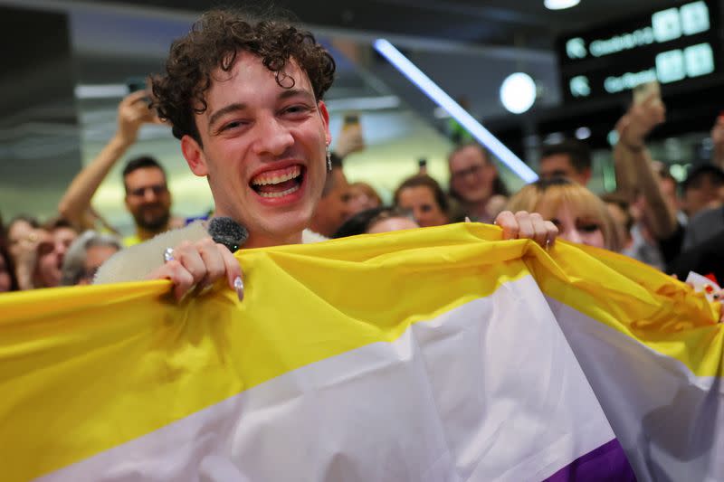 Nemo, cantante de Suiza, sostiene una bandera no binaria en un recibimiento de sus seguidores en el aeropuerto de Zúrich tras ganar el Festival de la Canción de Eurovisión 2024, en Kloten, Suiza