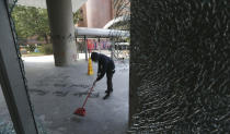 A protestor sweeps broken glass at the Hong Kong Polytechnic University in Hong Kong, Saturday, Nov. 16, 2019. Rebellious students and anti-government protesters abandoned their occupation of at least one major Hong Kong university after a near weeklong siege by police, but some other schools remained under control of demonstrators on Saturday. (AP Photo/Achmad Ibrahim)