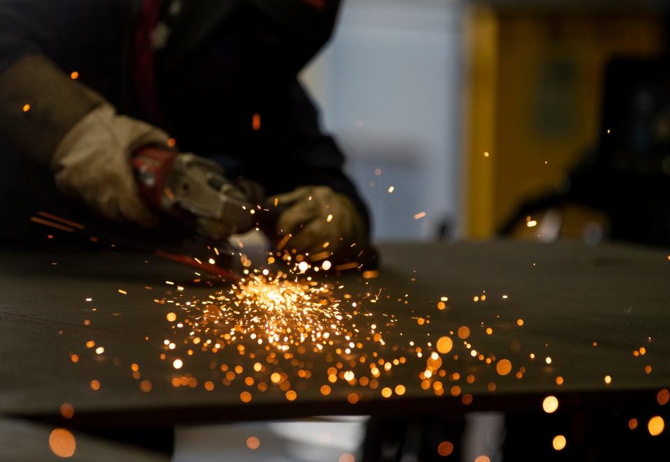 Sparks fly as Magdalene Fett grinds down a weld on Aug. 22, 2022, at Renco Machine Inc., in Green Bay, Wis.