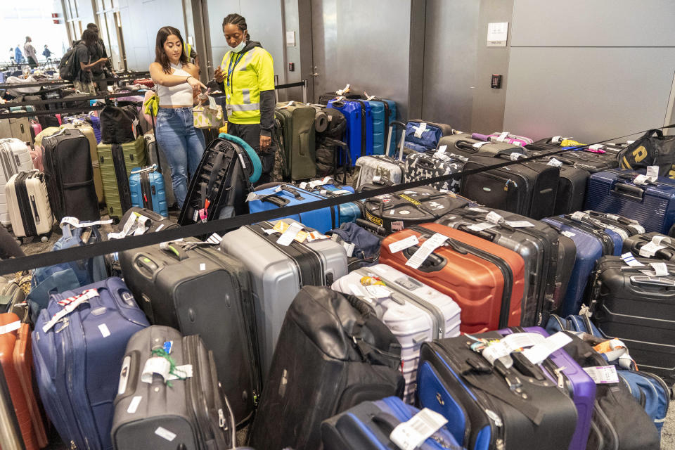 An airline employee, right, helps a traveler find her suitcase amongst the unclaimed luggage in the arrivals area of Terminal B at LaGuardia Airport, Tuesday, June 27, 2023, in New York. Travelers waited out widespread delays at U.S. airports on Tuesday, an ominous sign heading into the long July 4 holiday weekend, which is shaping up as the biggest test yet for airlines that are struggling to keep up with surging numbers of passengers. (AP Photo/Mary Altaffer)