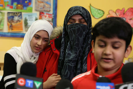 Khawlah Noman, 11, embraces her mother Saima Samad as her brother Mohammed Zakariyya, 10, speaks to reporters at Pauline Johnson Junior Public School, in Toronto, Ontario, Canada January 12, 2018. REUTERS/Chris Helgren