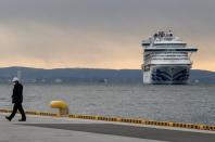 Foto del jueves de un trabajador con una máscara en el puerto de Yokohama cerca de un crucero en el que 10 pasajeros dieron positivo de coronavirus