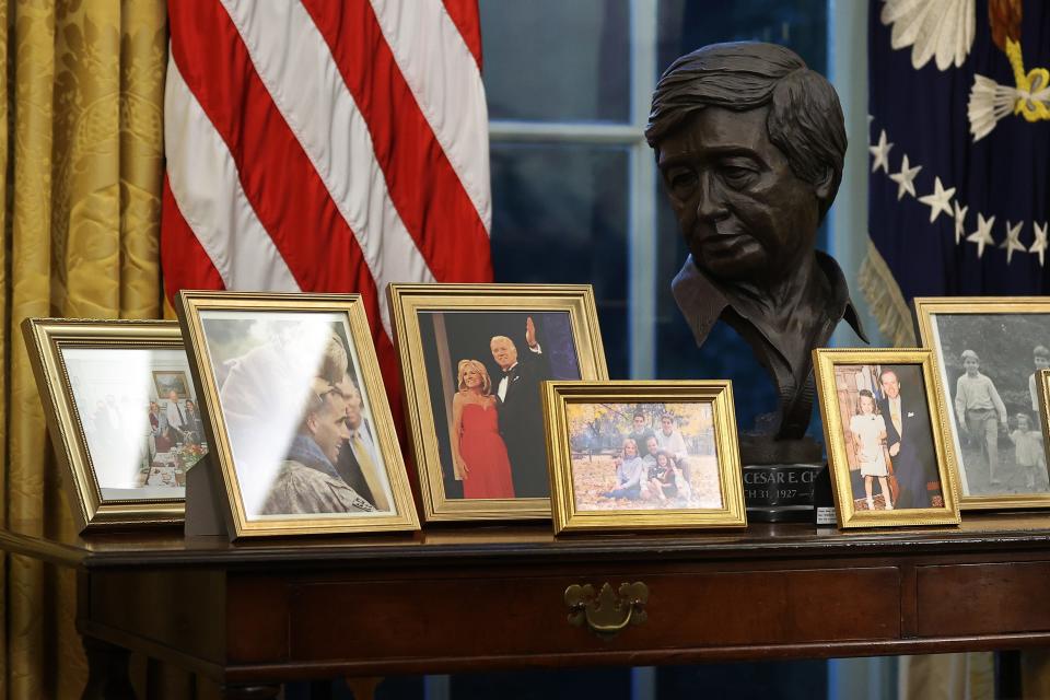 A bronze bust of Mexican-American labor leader César Chávez overlooks photographs on a table behind the Resolute Desk in the Oval Office while President Joe Biden prepares to sign a series of executive orders just hours after his inauguration on Jan. 20, 2021, in Washington, D.C.