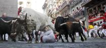 A steer jumps over a fallen runner as two Jandilla fighting bulls follow behind at the Mercaderes curve during the first running of the bulls of the San Fermin festival in Pamplona, northern Spain, July 7, 2015. Two runners were gored in the run that lasted 2 minutes and 23 seconds, according to local media. (REUTERS/Susana Vera)