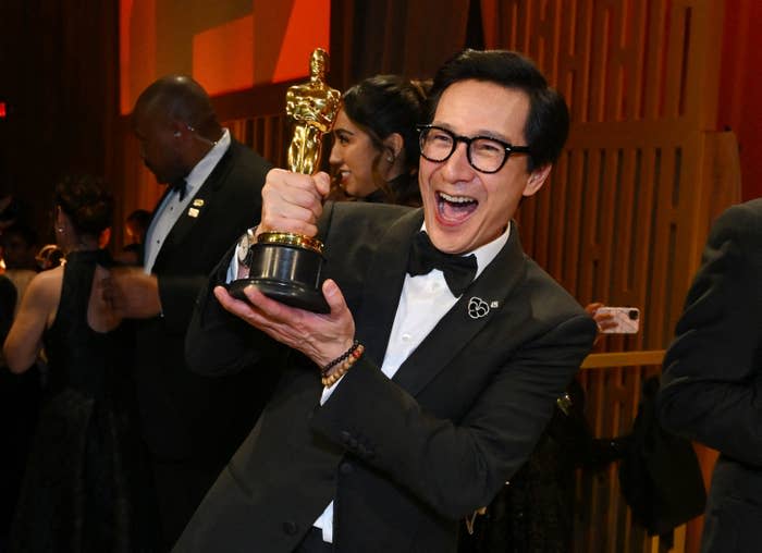 Ke Huy Quan holds his Oscar and smiles