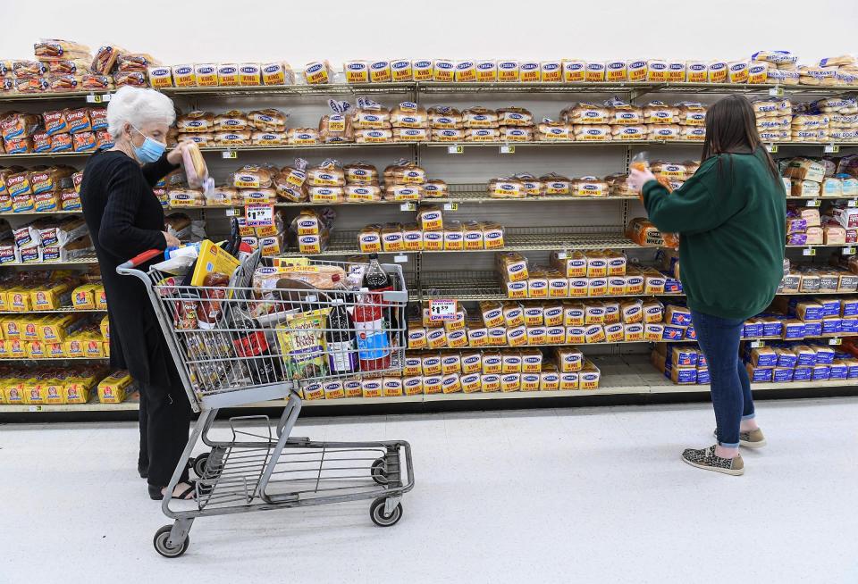 Loretta Pugh, left, of Anderson gets a loaf of bread near Maddison Kelly, an employee of Quality Foods in Anderson, S.C.  in January 2022.