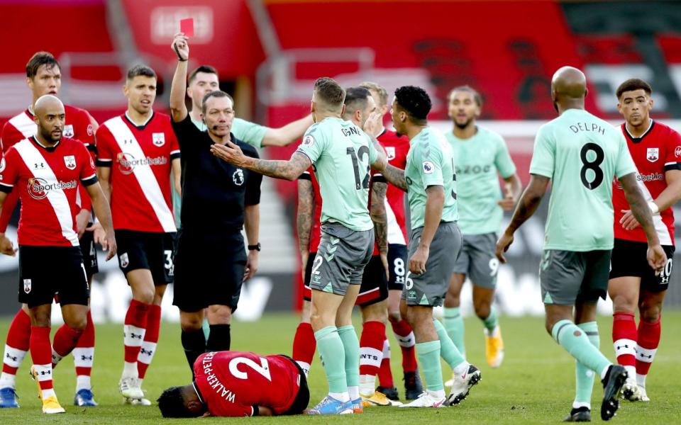 Everton's Lucas Digne (centre) is shown a red card by referee Kevin Friend after fouling Southampton's Kyle Walker-Peters (floor) during the Premier League match at St Mary's Stadium, Southampton. - PA