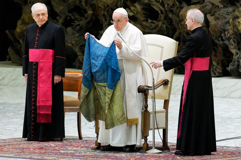 Pope Francis shows a flag that he said was brought to him from Bucha, Ukraine