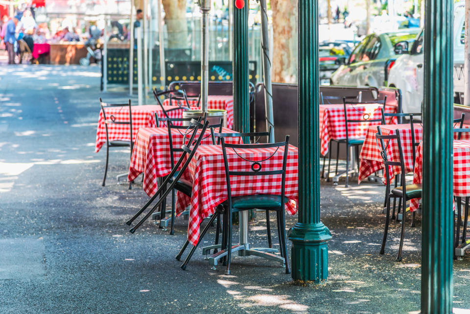 Empty chairs and tables at an outdoor cafe. (Source: Getty)