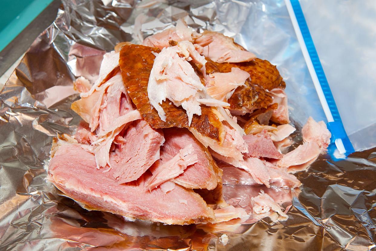 Closeup of cut turkey leftovers from a big dinner on aluminum foil with a plastic zipper bag