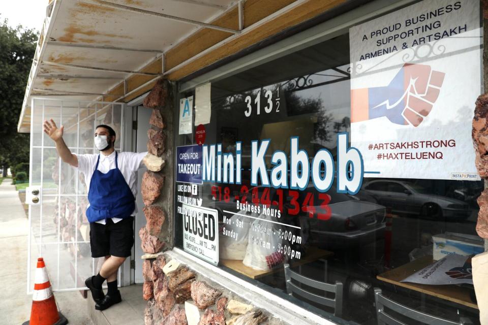 Armen Martirosyan waves to a passerby at his restaurant, Mini Kabob, in Glendale