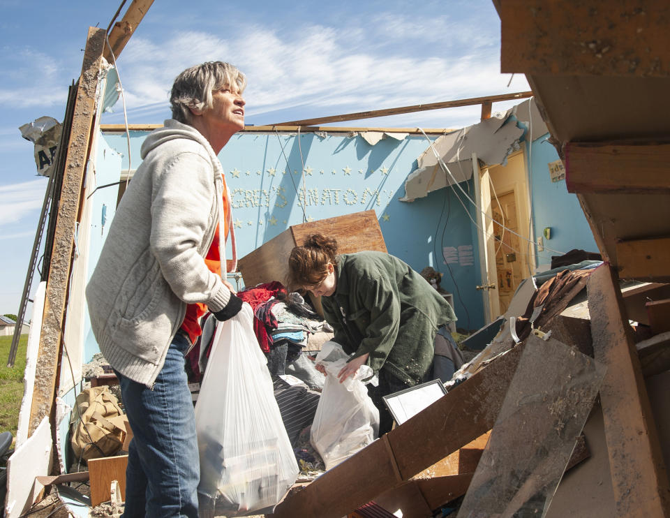 Stephanie Fatheree, right, salvages items from her house damaged from the tornado the previous night with help from a neighbor on Thursday, April 9, 2020, in Harrisburg, Ark. Fatheree said she took shelter with her mother, Angie, in the bathroom during the tornado. Severe storms with high winds, hail and possible tornadoes have caused damage to dozens of homes and businesses in parts of Indiana and Arkansas. (Quentin Winstine/The Jonesboro Sun via AP)