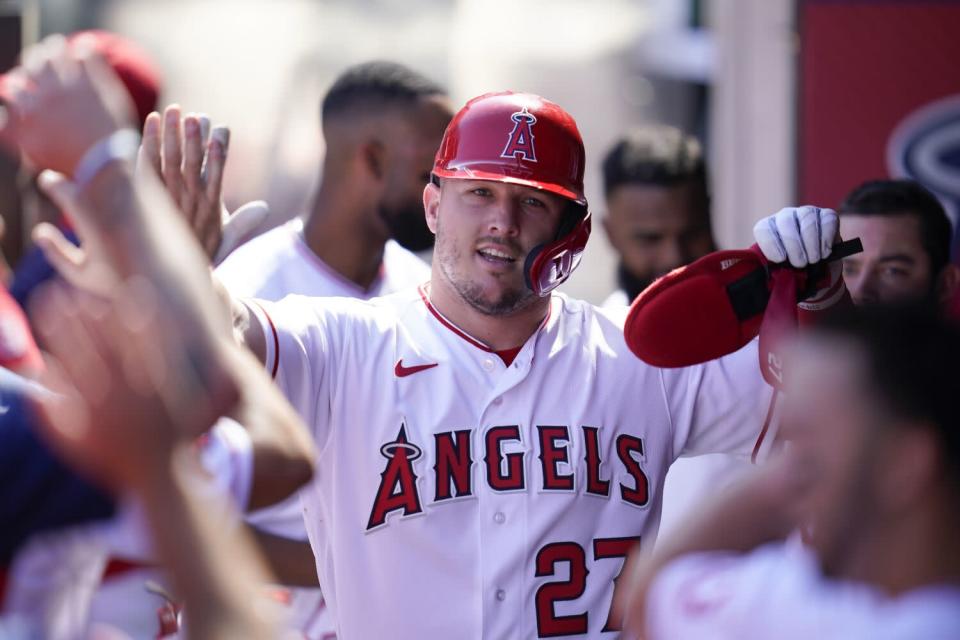 Mike Trout celebrates in the dugout after scoring a single off Taylor Ward during Sunday's first game.