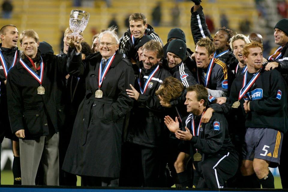 Crew owner Lamar Hunt holds up the Lamar Hunt U.S. Open Cup trophy after his team won the finals in 2002.