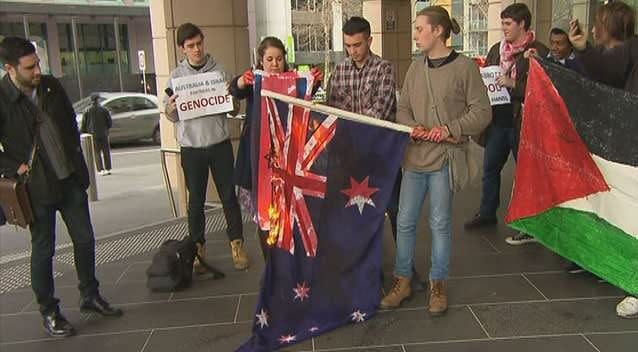 Students burn an Australian flag during a pro-Palestinian rally in Melbourne. Photo: 7News
