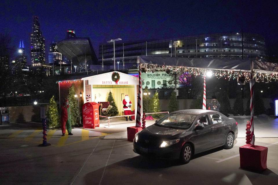 A car drives through Santa's Garage past the social distant Santa, on the roof of a parking garage next to Soldier Field and a backdrop of the Chicago skyline on Dec. 10, 2020. In this socially distant holiday season, Santa Claus is still coming to towns (and shopping malls) across America but with a few 2020 rules in effect. (AP Photo/Charles Rex Arbogast)