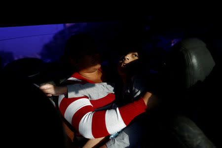 Karla Martines carries her son Jose Gregorio Anton, 11, a neurological patient being treated with anticonvulsants, while they ride in a car in La Guaira, Venezuela February 20, 2017. REUTERS/Carlos Garcia Rawlins