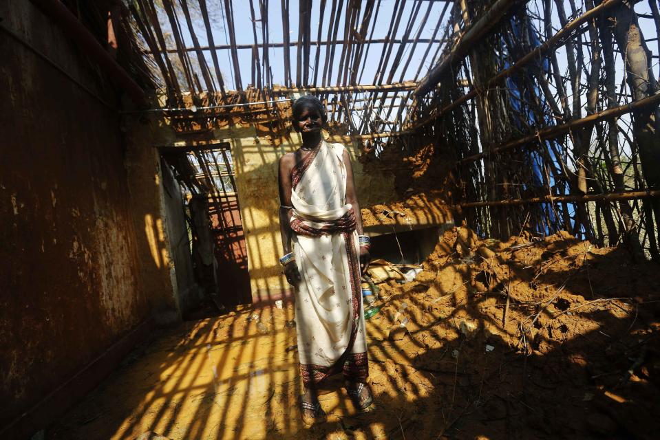 A woman stands inside her damaged house after Cyclone Phailin hit Gopalpur village