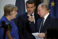 German Chancellor Angela Merkel listens to French President Emmanuel Macron, center, and Russian President Vladimir Putin during a joint press conference with Ukrainian President Volodymyr Zelenskiy, at the Elysee Palace in Paris, Monday Dec. 9, 2019. Russian President Vladimir Putin and Ukrainian President Volodymyr Zelenskiy met for the first time Monday at a summit in Paris to try to end five years of war between Ukrainian troops and Russian-backed separatists. (Charles Platiau/Pool via AP)