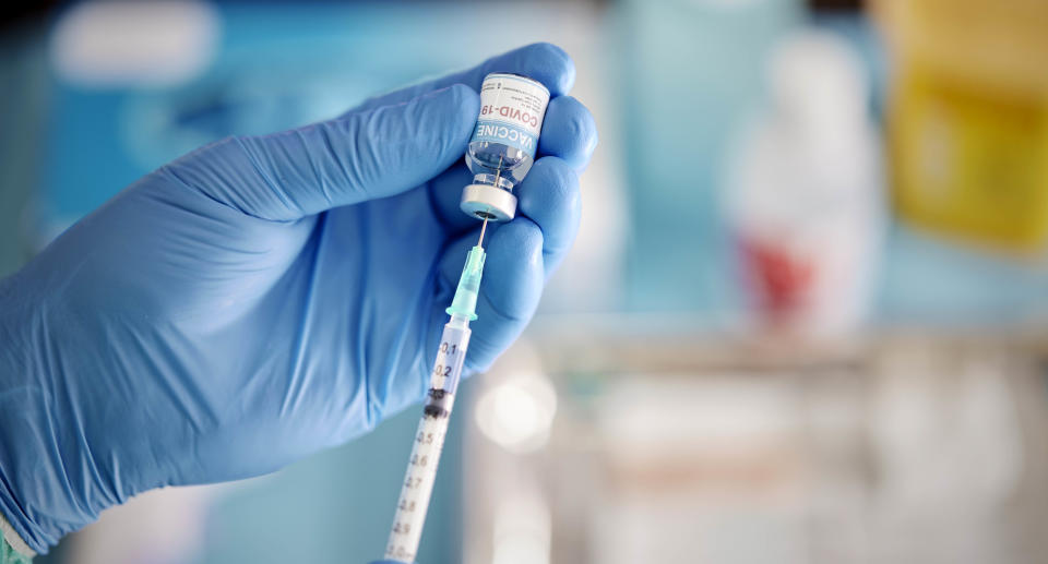 A healthcare Worker hands in surgical gloves pulling COVID-19 vaccine liquid from vial to vaccinate a patient Source: Getty Images 