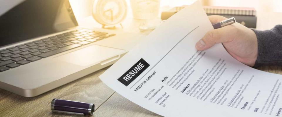 Businessman or job seeker review his resume on his desk before send to finding a new job with pen, necktie, glasses and digital tablet.