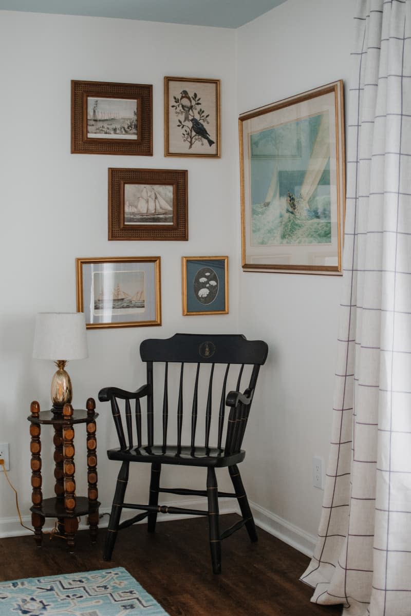 Chair in corner of room surrounded by art.