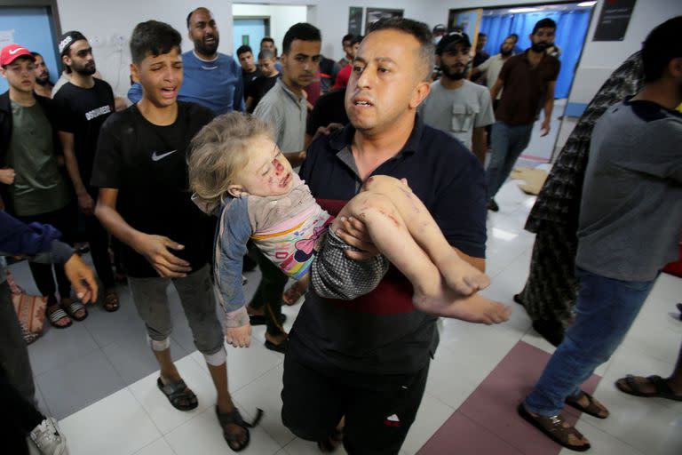 Un niño llora mientras un hombre entra corriendo al hospital Al-Shifa con un niño en brazos tras el bombardeo israelí que afectó una casa en el barrio Mansura de la ciudad de Gaza, en el suburbio oriental de Shujaiya el 4 de noviembre de 2023