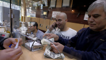 A currency exchange dealer counts U.S. dollar banknotes at his shop in a shopping centre in northern Tehran, January 17, 2016. REUTERS/Raheb Homavandi/TIMA/File Photo