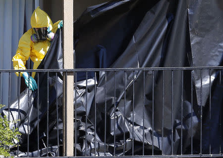 A worker wearing a hazardous material suit puts up a tarp at the apartment unit where Thomas Eric Duncan, a Liberian citizen diagnosed with the Ebola virus, was staying in Dallas, Texas, October 3, 2014. REUTERS/Jim Young