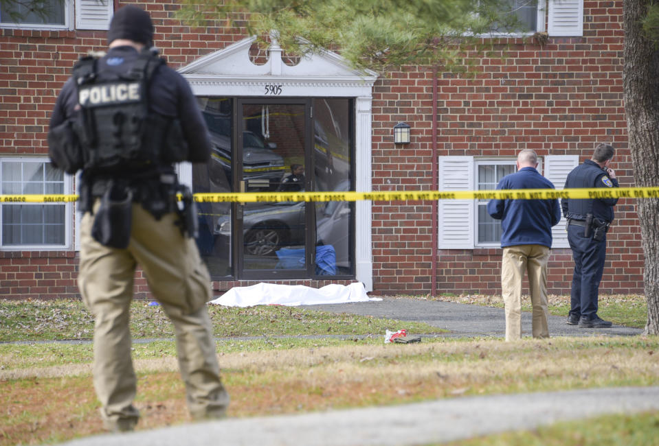 Law enforcement personnel work at the scene which appears to show a body covered under a white blanket outside of an apartment, Wednesday, Feb. 12, 2020, in Baltimore. Two law enforcement officers with a fugitive task force were injured and a suspect died in the shooting, the U.S. Marshals Service said. (Ulysses Muñoz/The Baltimore Sun via AP)