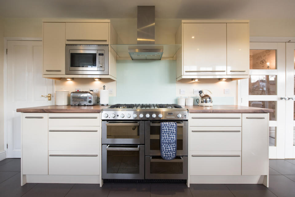 kitchen with a range overhead and microwave in a cabinet to the left