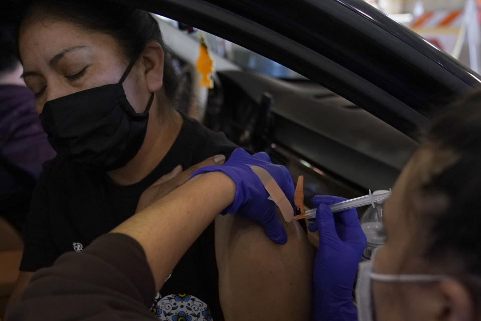 Jamie Yeini receives a shot of the Moderna COVID-19 vaccine from Melisa Alavarez, right, at the at a Sacramento County drive-thru vaccination center at the California Exposition & State Fair grounds in Sacramento, Calif., Thursday, Jan. 21, 2021. Local officials and businesses in the 13-county Greater Sacramento region were caught off guard last week when outdoor dining and worship services were OK again, hair and nail salons and other businesses could reopen, and retailers could allow more shoppers inside. It's still a mystery how the state made the decision or how and when it will lift the most serious restrictions on the bulk of the state's population because officials won't share their data. (AP Photo/Rich Pedroncelli)