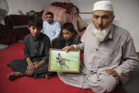 In this Thursday, May 30, 2019 photo, Noor Mohammad, who fled his village in Nangarhar in late April as Islamic State group fighters swept through the area, shows a picture of his son, a soldier in the army who died in Helmand Province fighting the Taliban, during an interview with The Associated Press, in Jalalabad, Afghanistan. In recent months the Taliban has said it has no ambitions to monopolize power in a post-war Afghanistan, while IS is committed to overthrowing the Kabul government on its path to establishing a global caliphate. (AP Photo/Rahmat Gul)