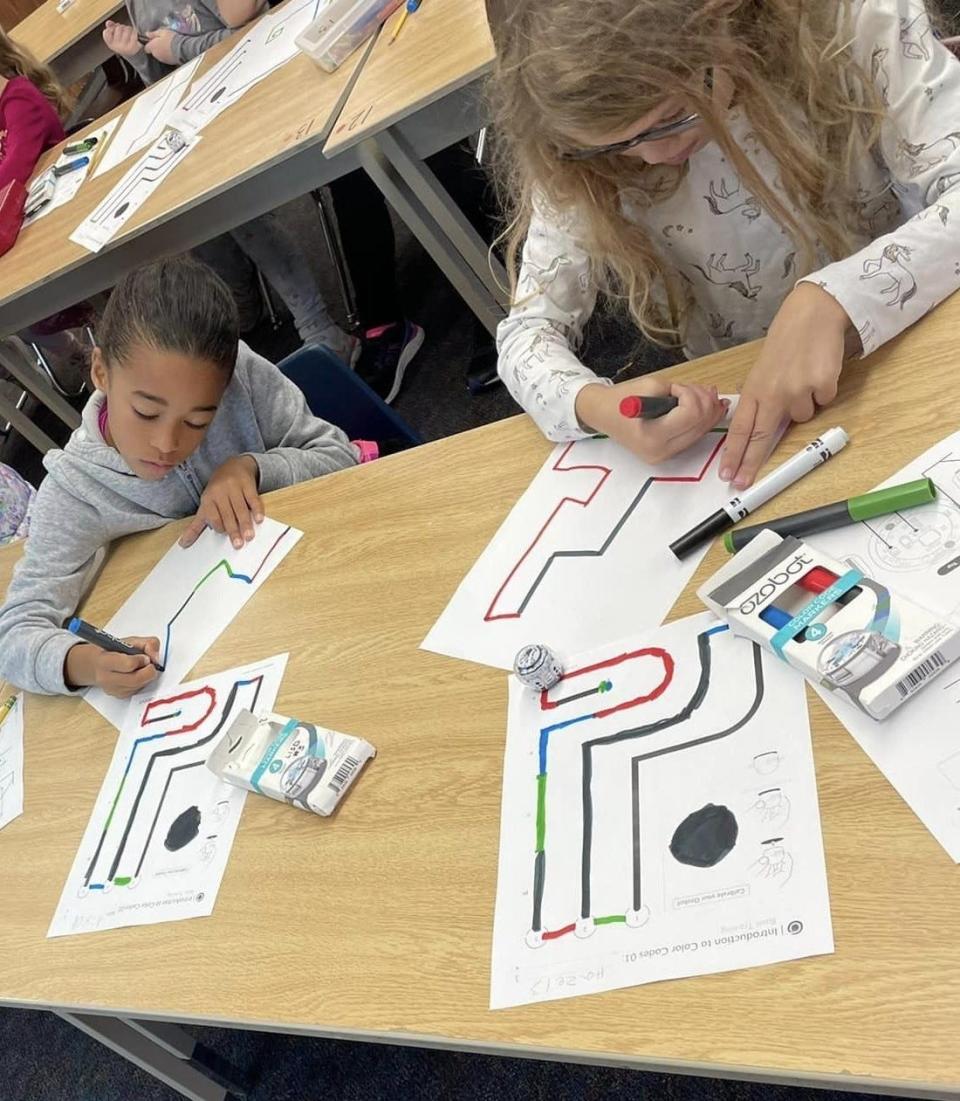 Makenzie Palmer, left, and Hazel Berna do their initial lesson work in the classroom. OzoBots use sensors to follow lines and color codes.