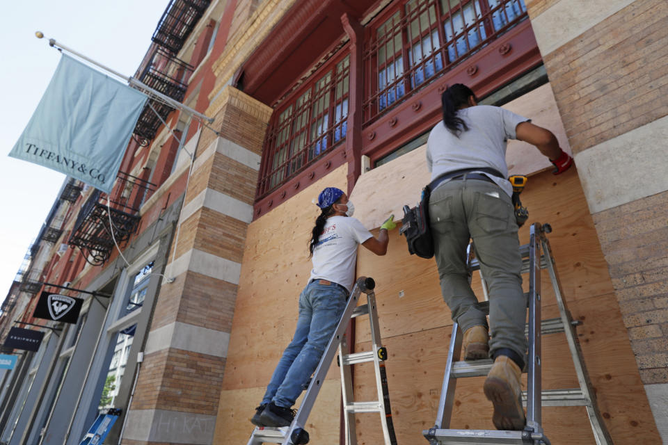 Workers board up the windows of a Tiffany's store in SoHo, New York City, on Sunday. (Photo: ASSOCIATED PRESS)