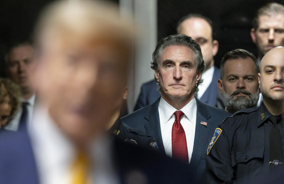 FILE - Republican North Dakota Governor Doug Burgum listens as former President Donald Trump, in foreground, talks to reporters at Manhattan criminal court, May 14, 2024, in New York. Burgum is one of Trump’s most visible and vocal backers, sprinting around the country to drum up support while auditioning to be his running mate. Meanwhile, Burgum is wrestling with a $5.5 billion carbon dioxide pipeline project in his home state. The venture has left him straddling an awkward political divide as Trump and President Joe Biden offer voters starkly different visions of America. (Justin Lane/Pool Photo via AP, File)