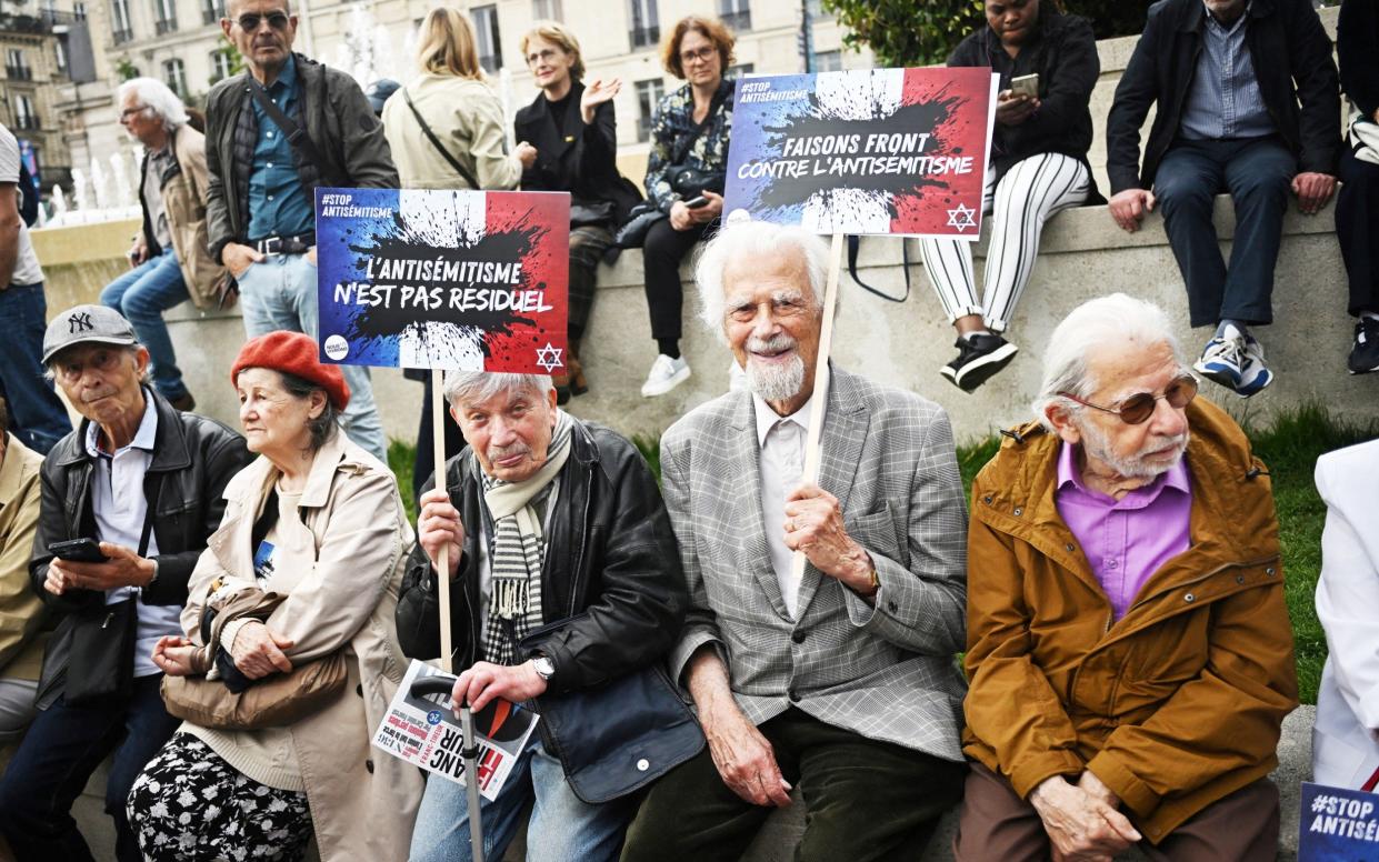 People attend a demonstration against anti-Semitism in front of Paris City Hall holding cards with slogans that read 'Anti-Semitism is not residual'