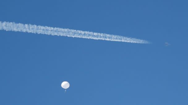 PHOTO: A jet flies by a suspected Chinese spy balloon as it floats off the coast in Surfside Beach, South Carolina, Feb. 4, 2023. (Randall Hill/Reuters)