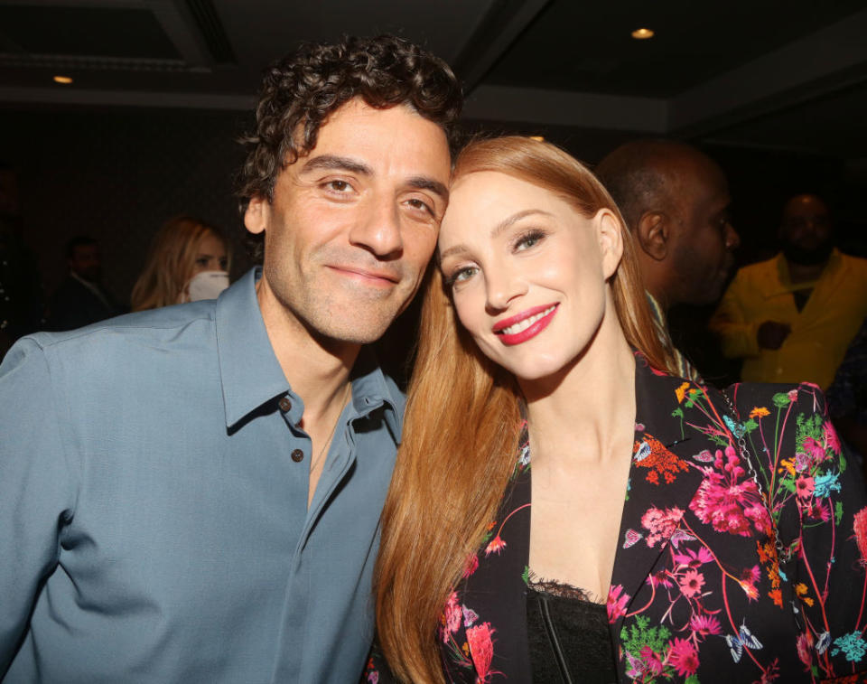 Two people smiling close together, one in a blue shirt, the other in a floral jacket